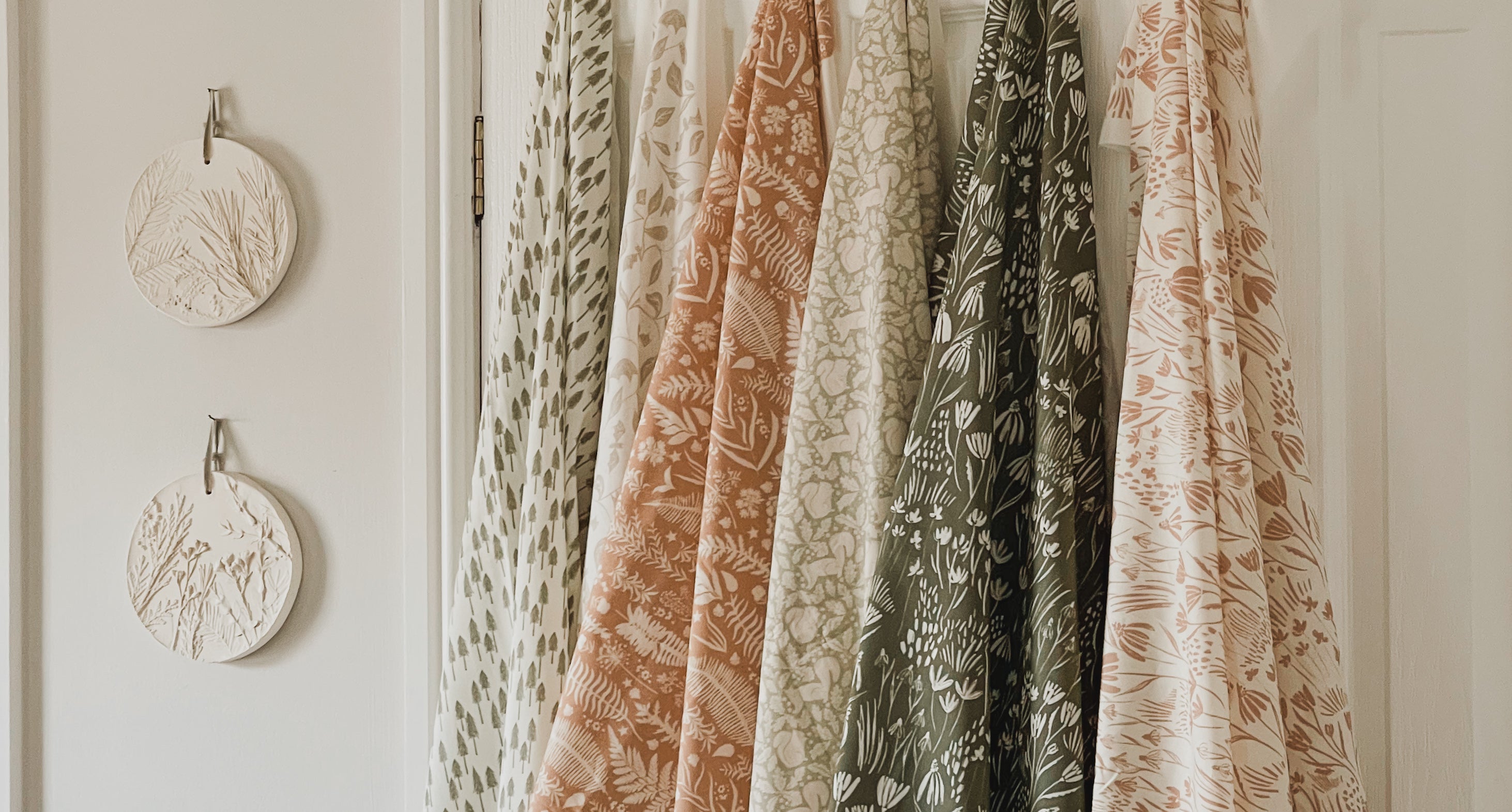 Nature-inspired fabrics in botanical prints on display, featuring eco-friendly materials by Hills & Hedgerows. English countryside-inspired fabric in various designs for cushions and lampshades.