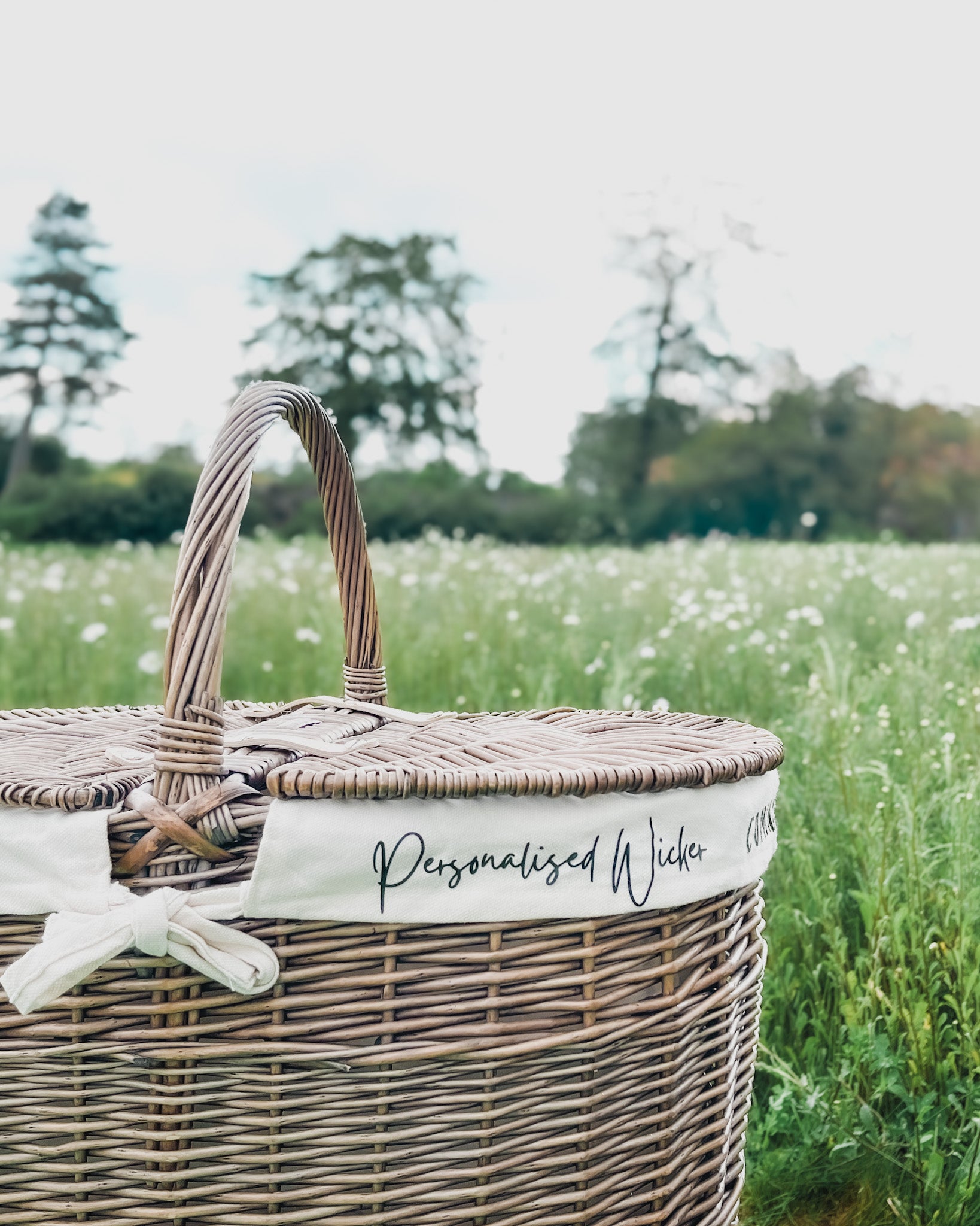 Personalised wicker picnic basket with custom font on removable cotton lining. Eco-friendly, handwoven willow with antique wash finish. Perfect for special occasions.