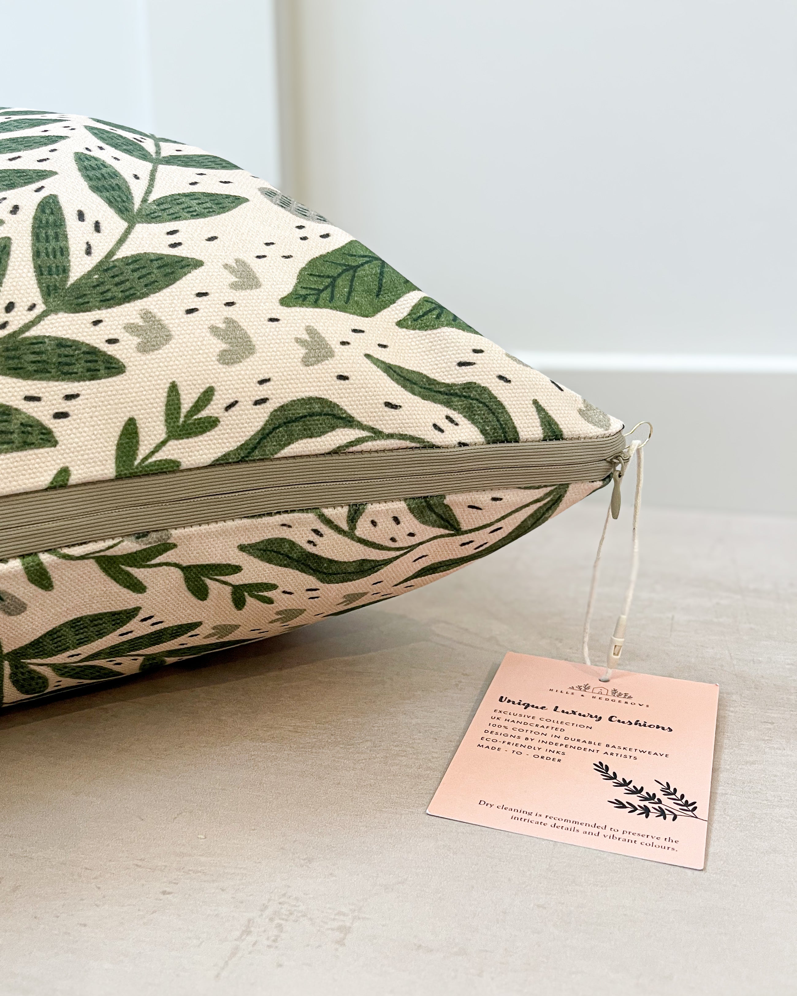 Botanical-inspired cushion with lush green and floral patterns, handmade in the UK from sustainable basketweave cotton. Olive Zip Design