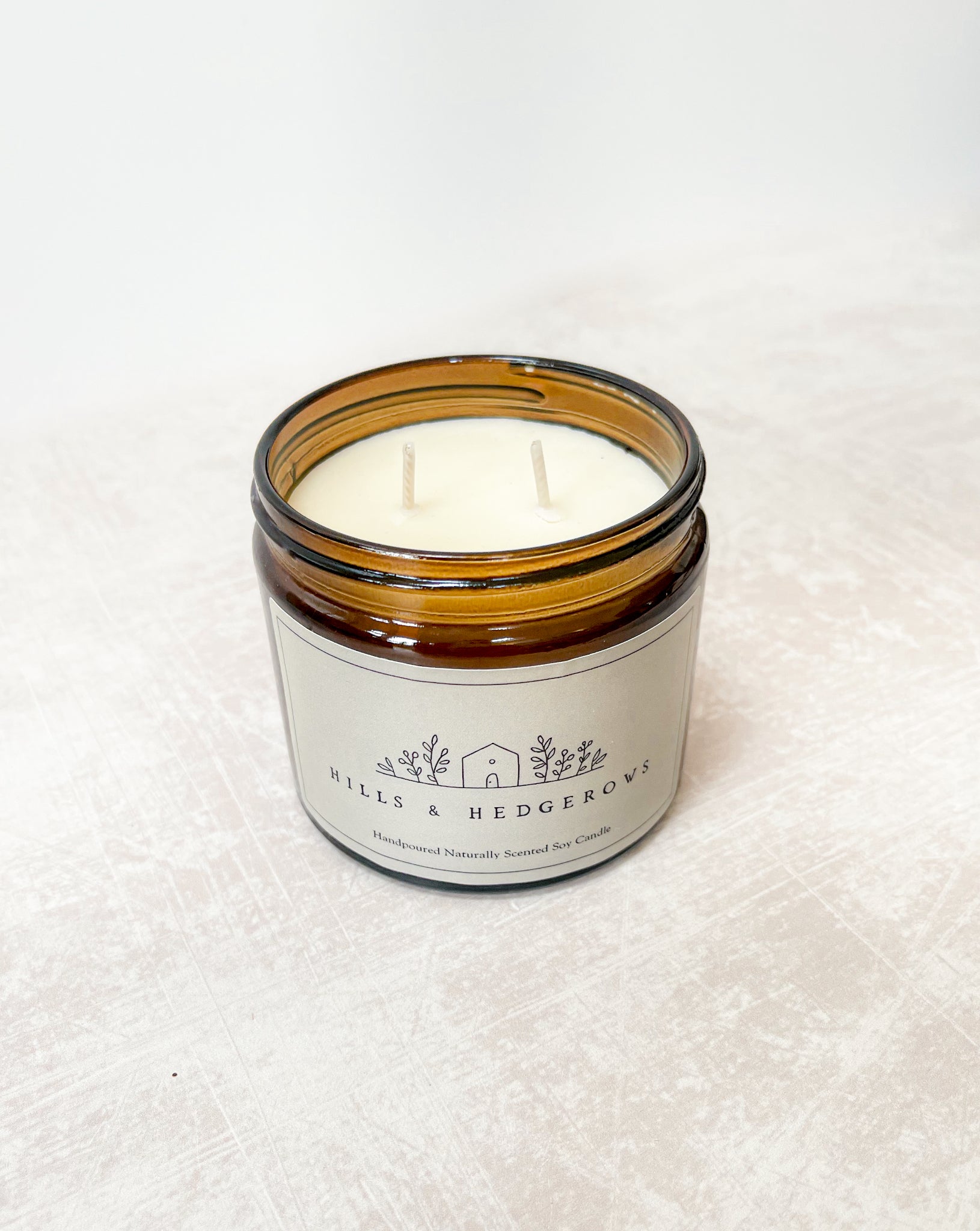 Crafted to evoke the warmth and tranquility of the countryside with our Hills and Hedgerows hand-poured naturally scented soy candle. Amber glass with green label, comes with Cotton pouch ready for gifting.