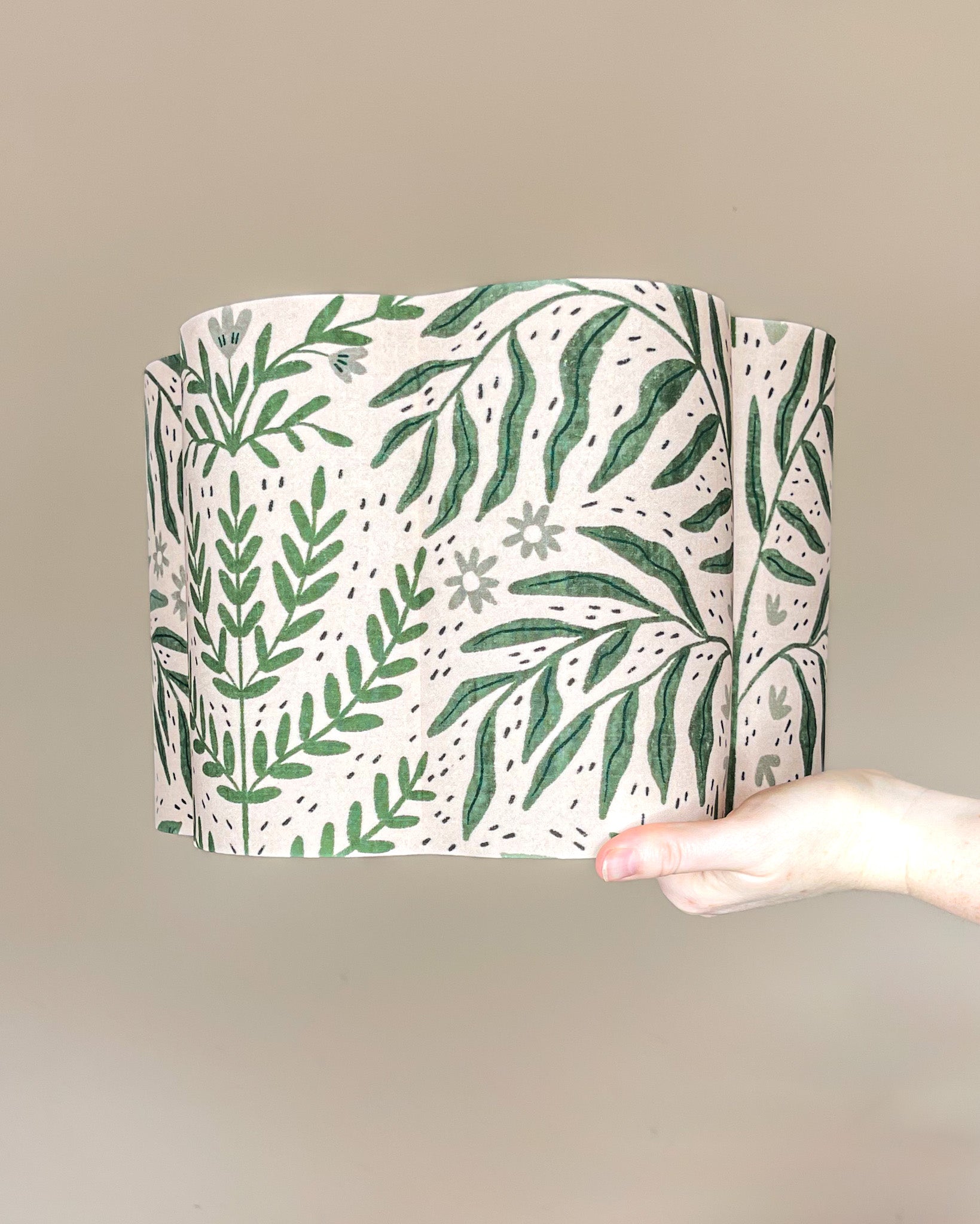 Tickling Greens scalloped cylinder lampshade with green leafy pattern over a blush cream background.