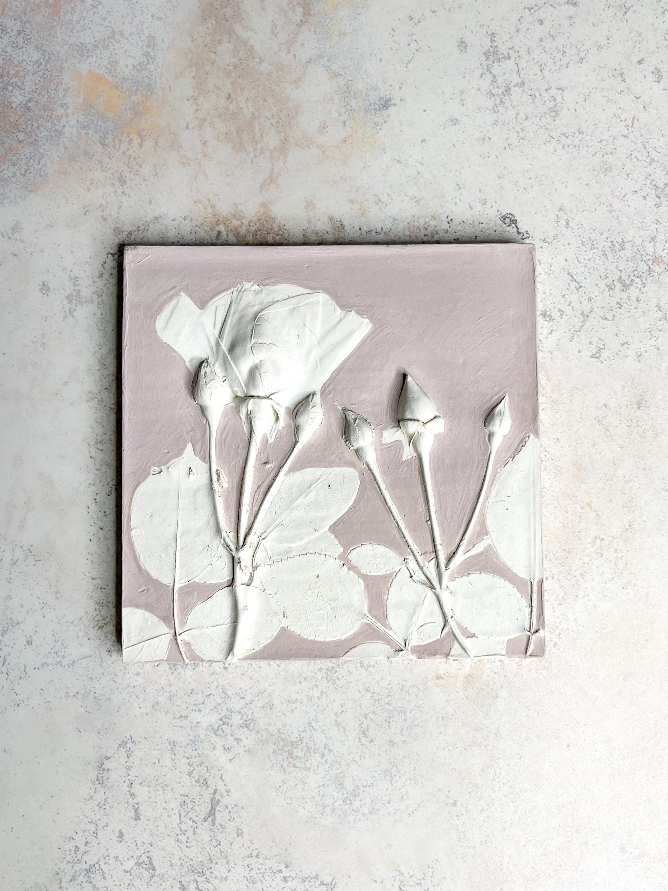 Handcrafted botanical relief tile featuring a rose imprint, hand-painted in muted blush pink, symbolising love and resilience