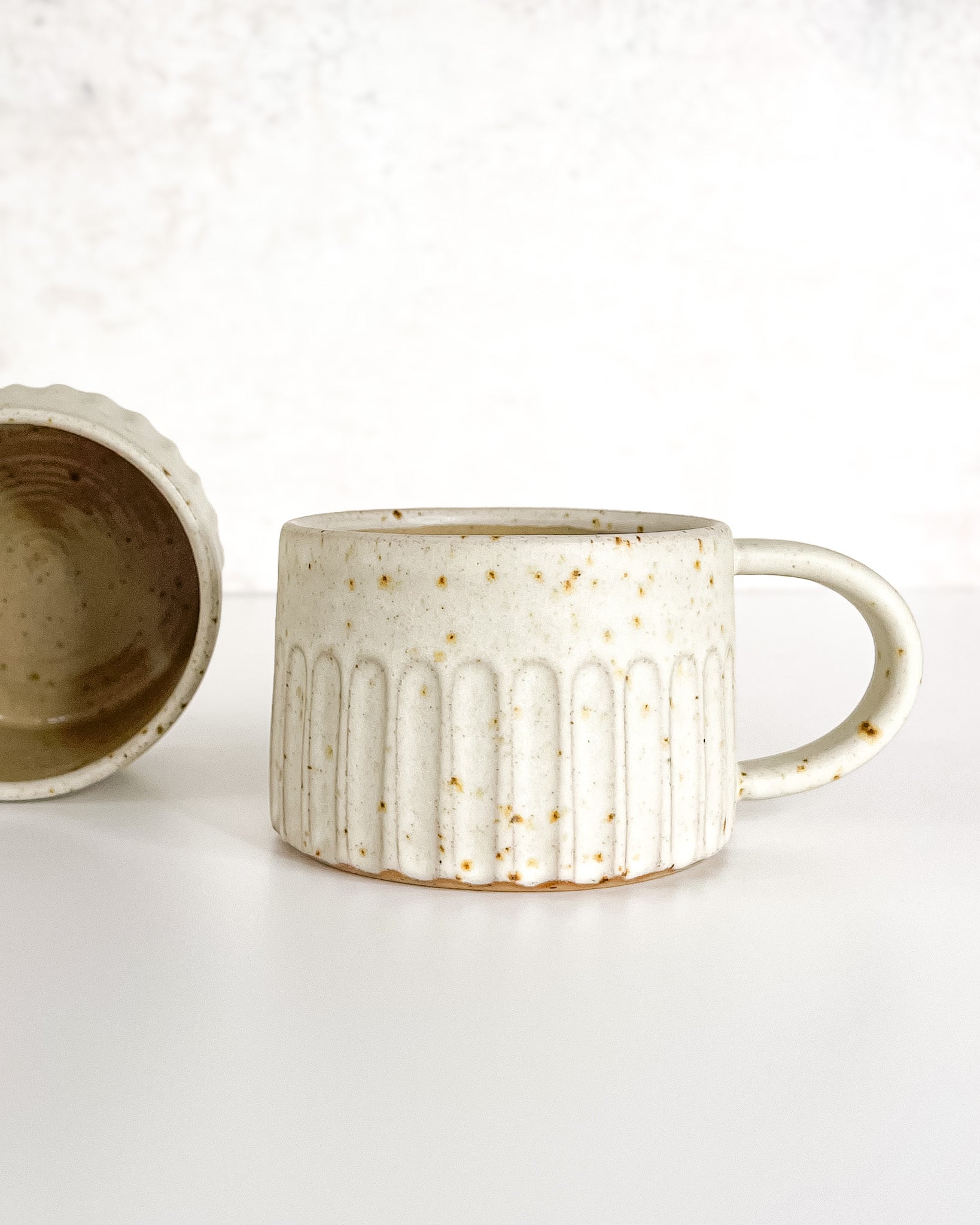 Hand-thrown carved and speckled stoneware cup with speckle glaze, ideal for coffee or tea.