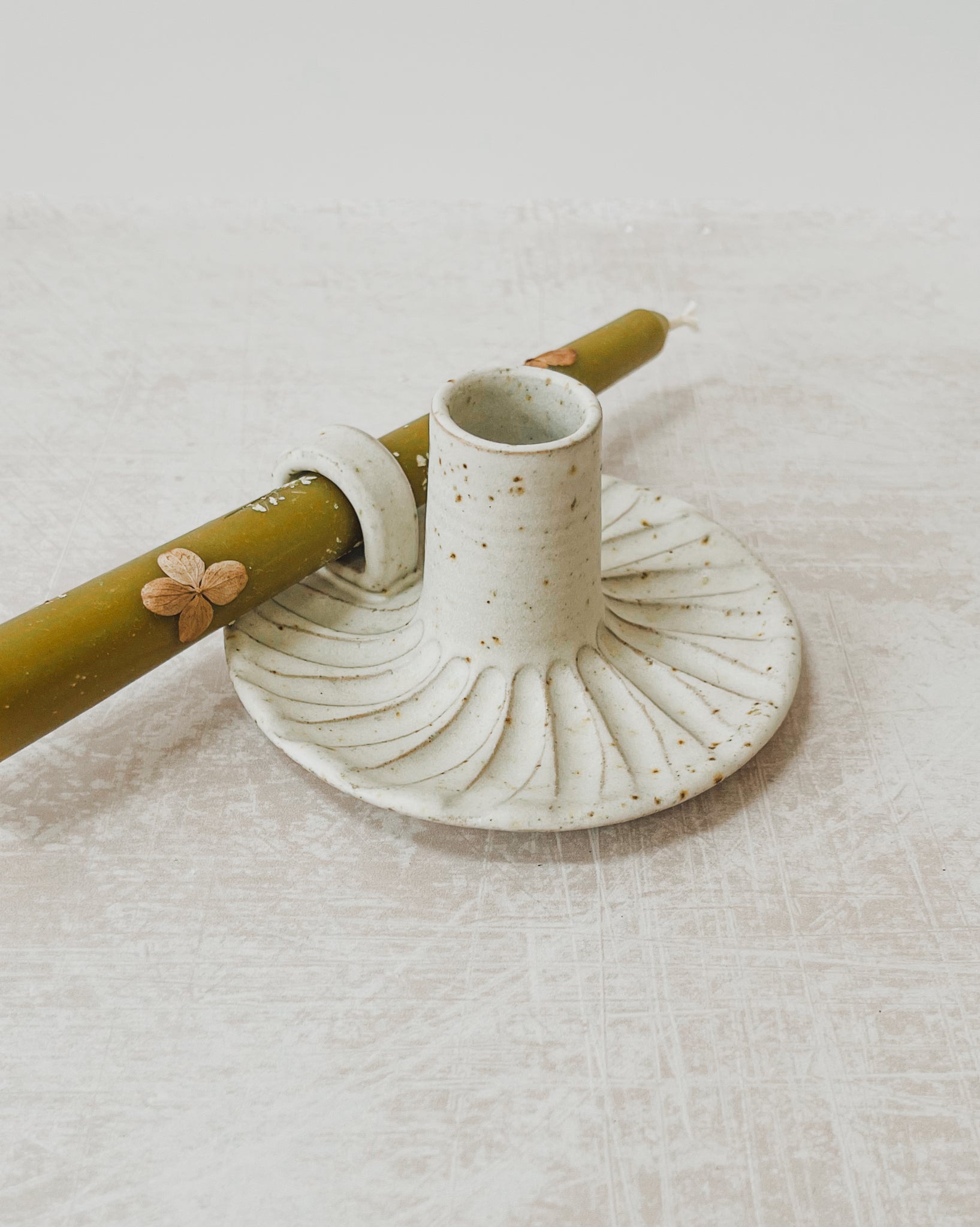 Handcrafted Ceramic Candle Holder with Decorative Beeswax Candles, featuring a speckled clay design with an off-white matte glaze, fluted finish, and looped handle, adorned with dried flowers.