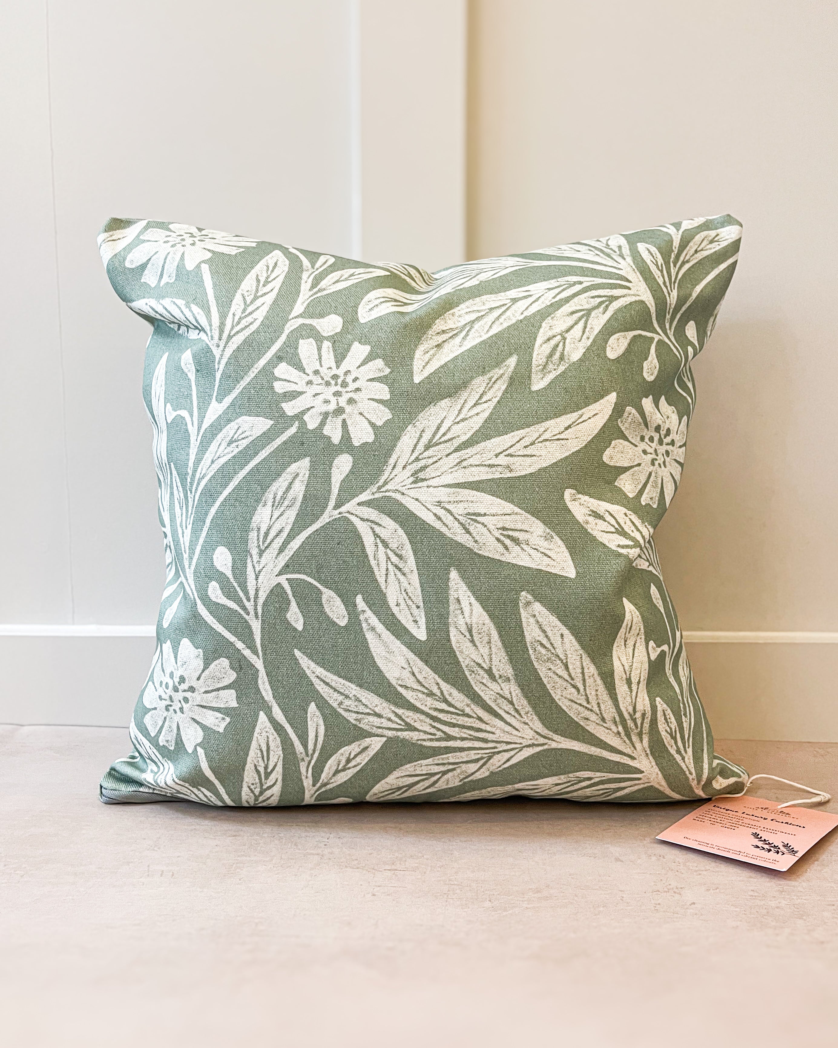 Botanical-inspired throw pillow with lush green and floral patterns, handmade in the UK from sustainable basketweave cotton.