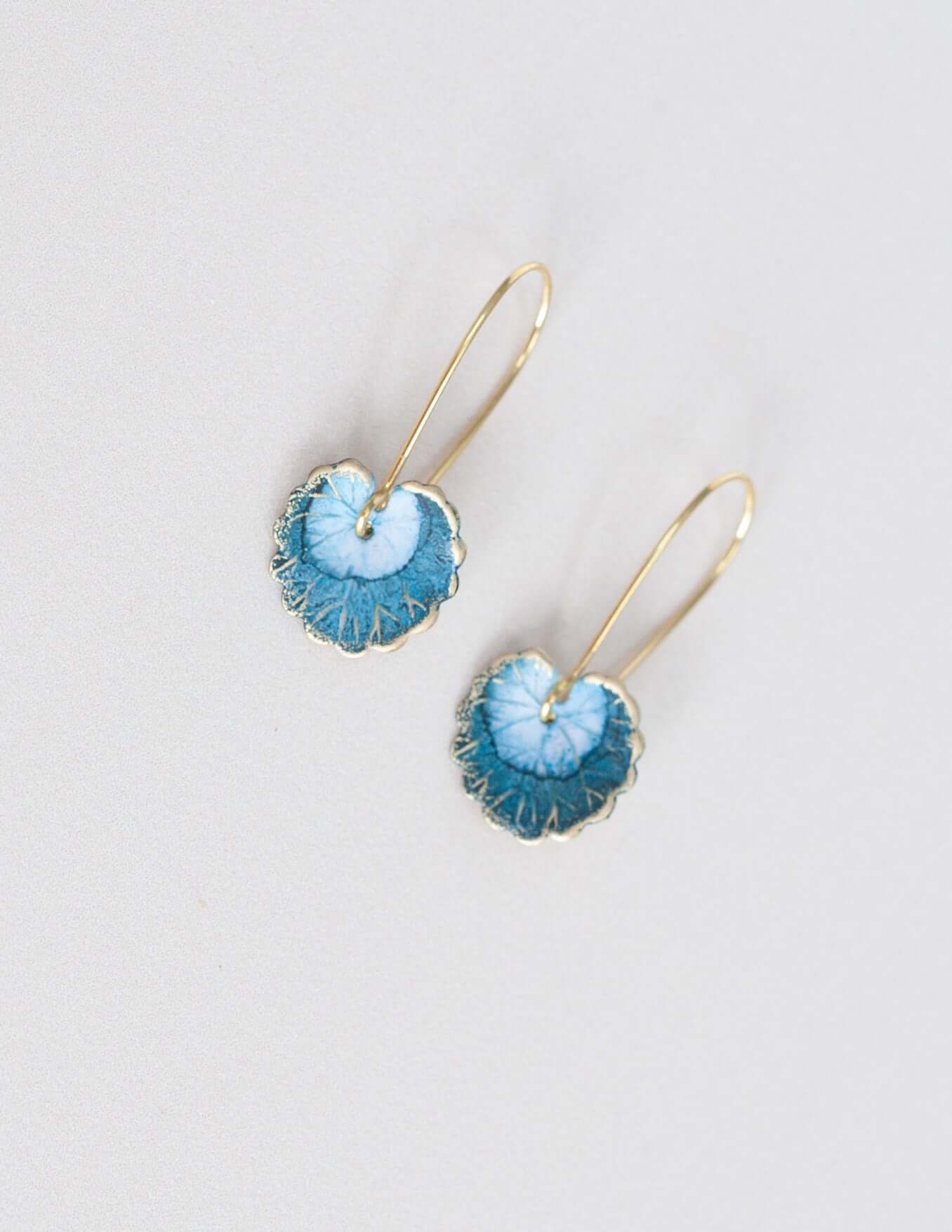 Handmade light blue lily leaf earrings with intricate brass charms and veining, featuring solid brass ear wires.