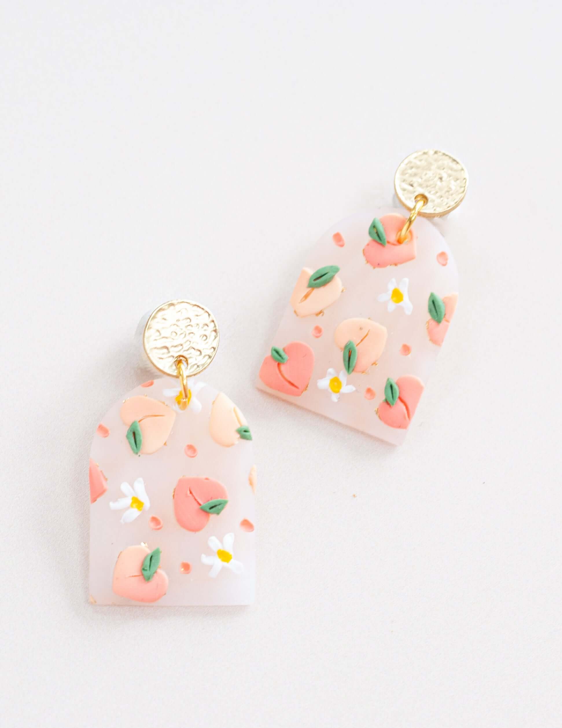 Handmade 'Blushing Peach' earrings with polymer clay petals and peach cuts, featuring surgical steel posts.