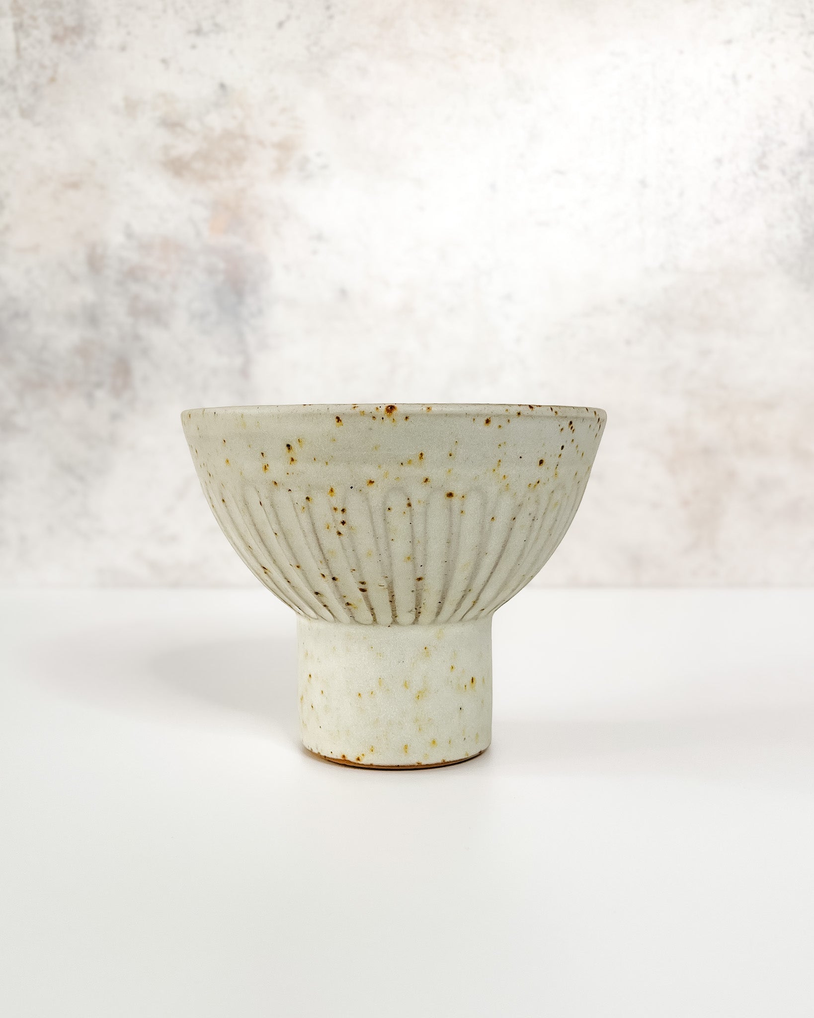 Hand-thrown ceramic Ikebana vase set with speckled clay, carved texture, and an elevated base, featuring a stem holder for floral displays.