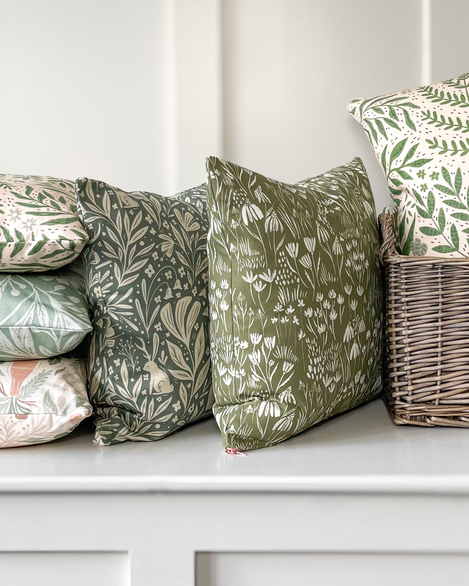 Wildflower Meadow Cushion featuring a warm deep green background with a cream wildflower pattern, made of basketweave cotton with a duck feather insert, designed by independent artists.