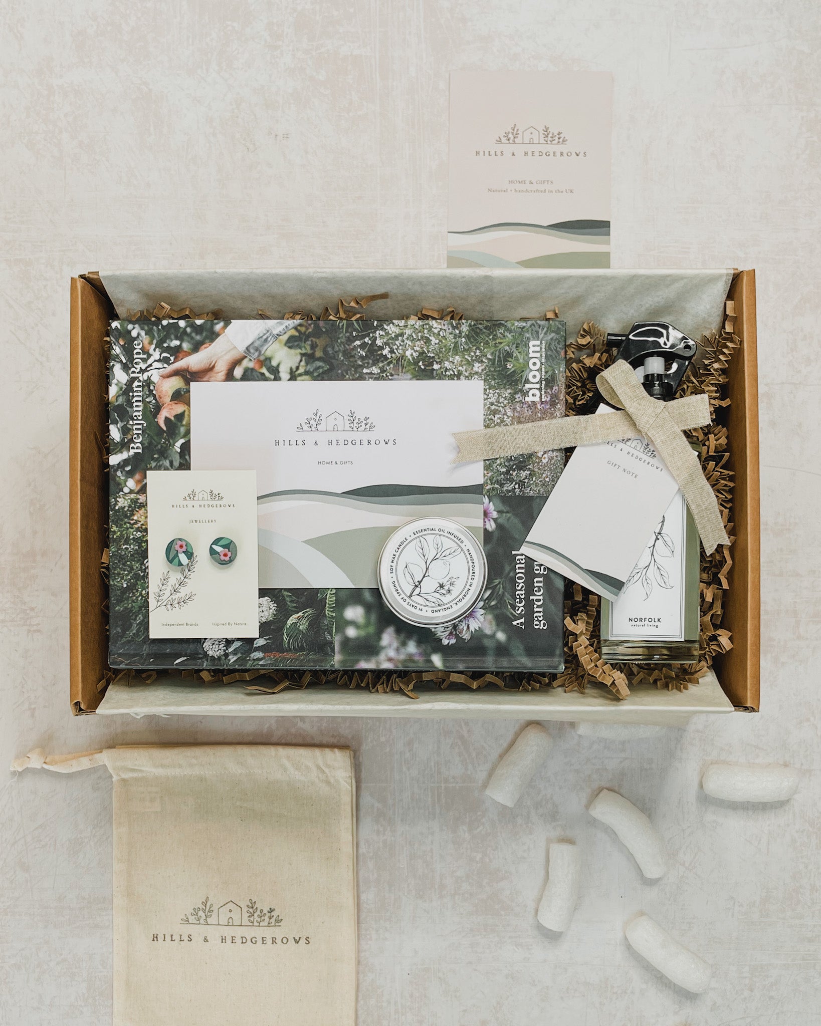 Beautifully curated Spring Renewal Gift Set featuring a spring room and mood mist, "What to Grow, Sow and Do" book, soy wax tea light candle, and polymer clay stud earrings with delicate green leaves and a small mauve flower, perfect for embracing the freshness of the season.