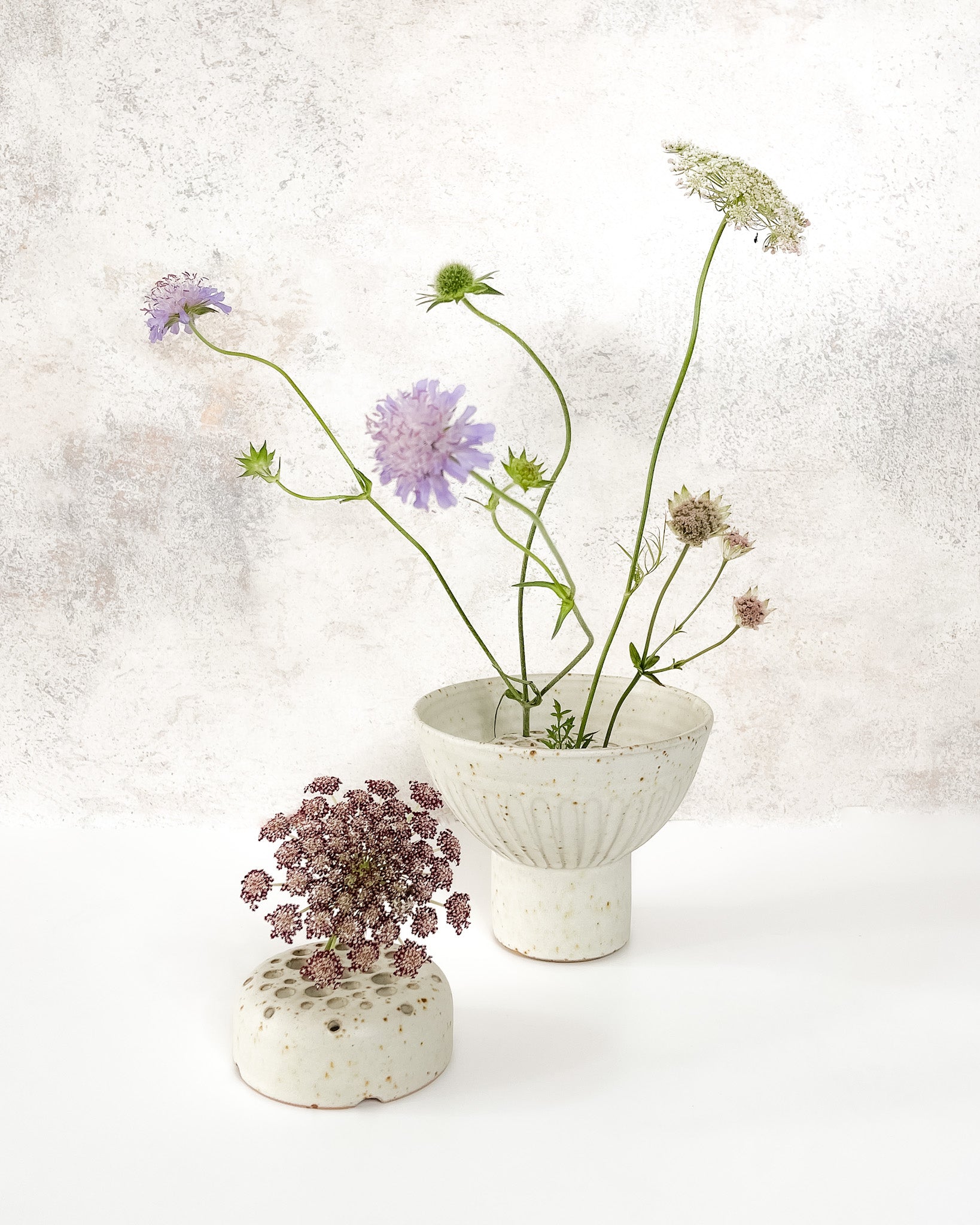 Hand-thrown ceramic Ikebana vase set with speckled clay, carved texture, and an elevated base, featuring a stem holder for floral displays.