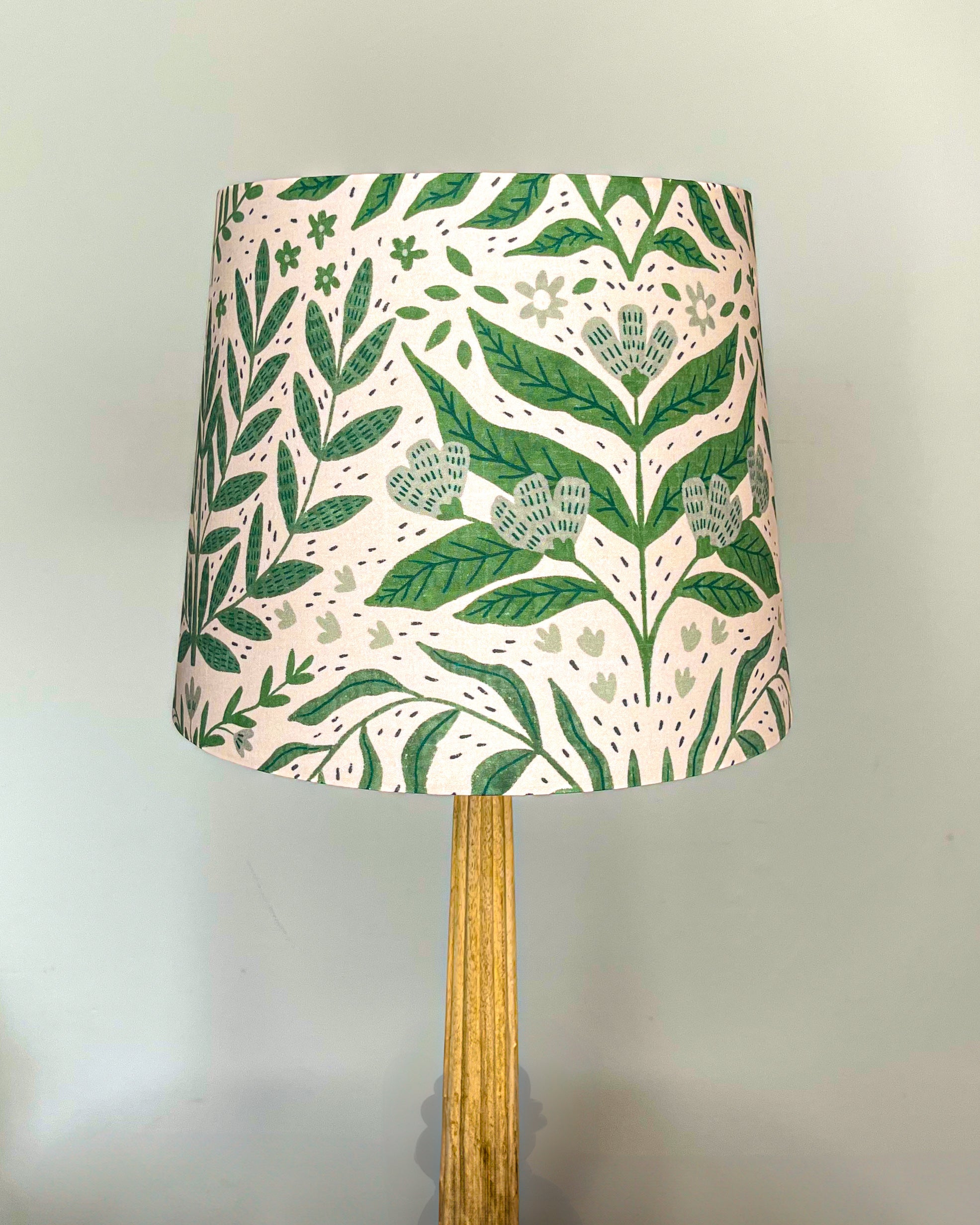 Tickling Greens Lampshade with intricate green leafy patterns and delicate floral accents on a blush cream background, handmade in the UK with cotton poplin, ideal for modern rustic home decor.