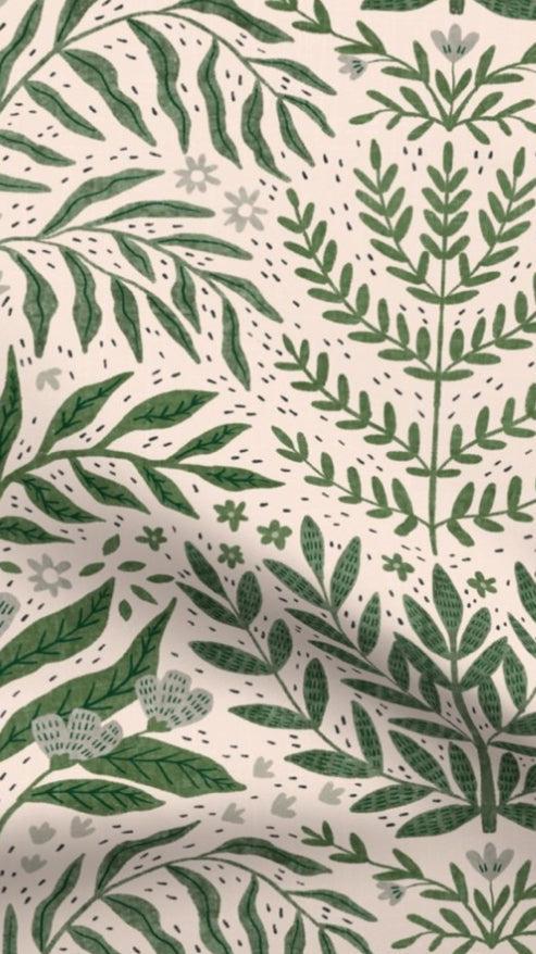 Tickling Greens fabric designed by independent artist Scarlet Soleil, featuring a green leafy botanical pattern and floral details on a blush cream background, eco-friendly cotton ideal for cushions and lampshades.